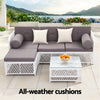Outdoor patio set with gray cushions and a coffee table on a patio with scenic background.