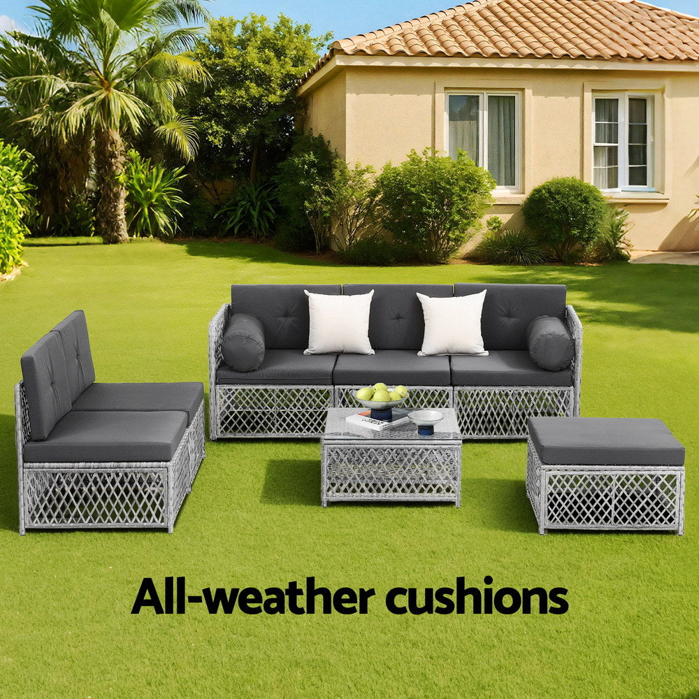Outdoor furniture set with gray cushions on a grassy lawn in front of a house.