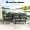 A Gardeon 4-seater Outdoor Aluminium Sofa Set with a two-seater sofa, two single sofas and a wide coffee table in charcoal black colour, seats are together forming an 'L' shape and set on a decked outdoor area with a lake view in the background.