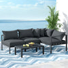 Gardeon 4-seater Outdoor Aluminium Sofa Set with a two-seater sofa, two single sofas which are placed together forming an 'L' shape with a matching coffee table with bowl of fruits on an outdoor balcony with an ocean view.