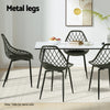 Dining table with four black chairs on a light wooden floor, featuring metal legs.