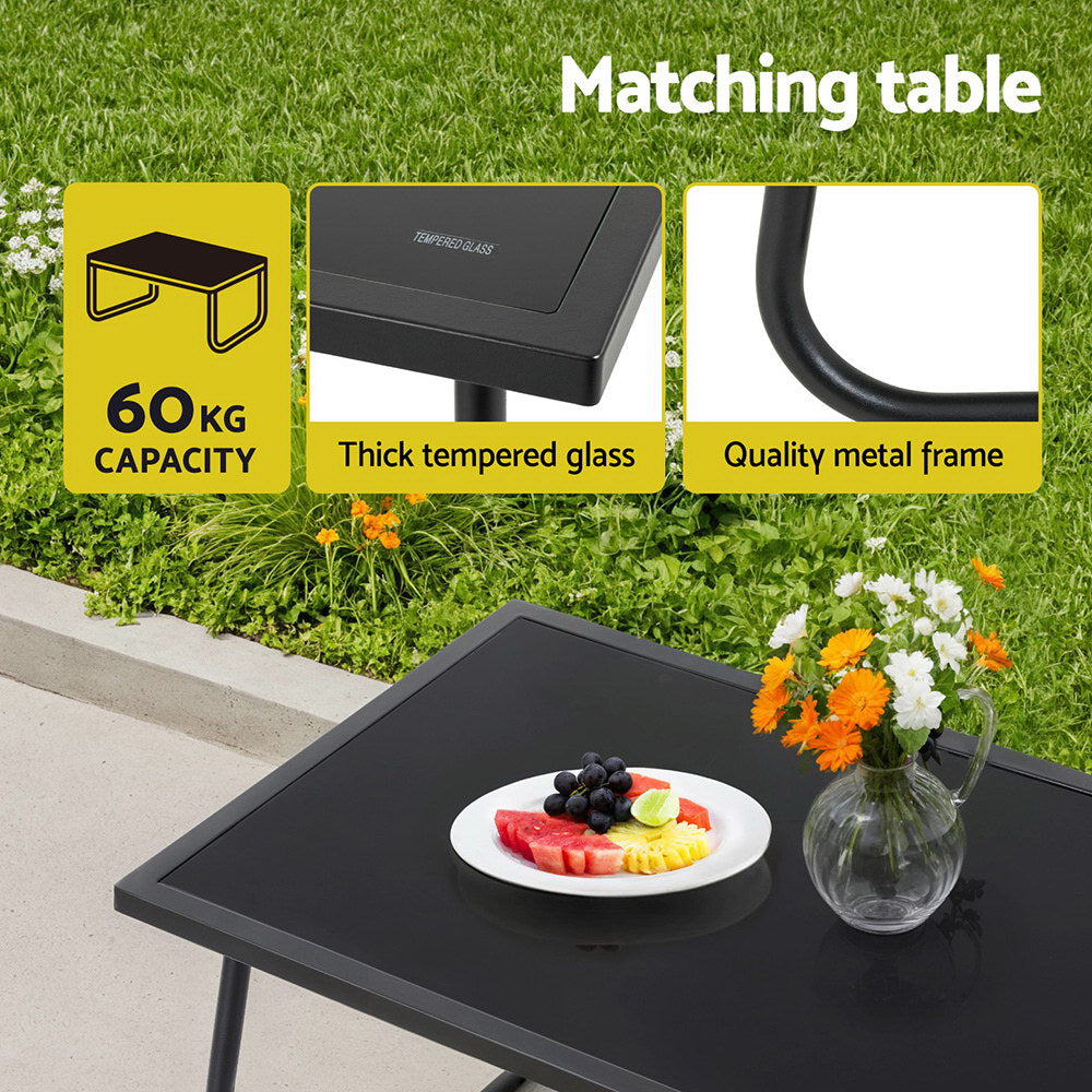 Black outdoor table with fruit plate and flowers on grass background, featuring text about capacity and materials.
