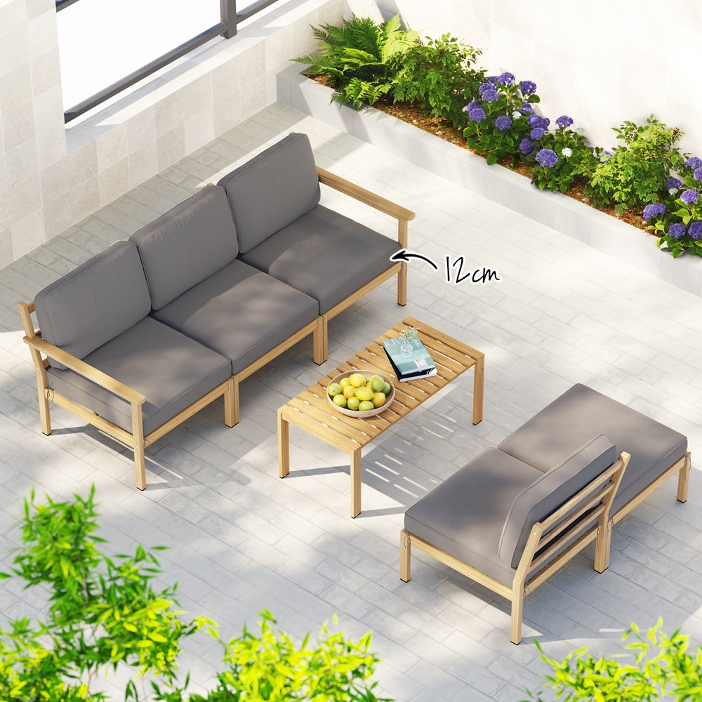 Outdoor furniture set with gray cushions and wooden frames on a patio with plants and flowers.