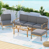 Outdoor furniture set with gray cushions on a patio with plants and a blue sky.
