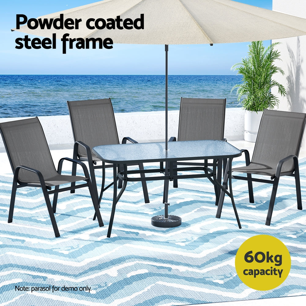 Outdoor furniture set with table and chairs under an umbrella on a beach setting.