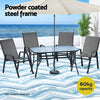 Outdoor furniture set with table and chairs under an umbrella on a beach setting.