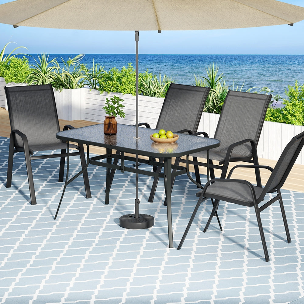 Outdoor patio set with table, chairs, and umbrella on a tiled patio with ocean view.