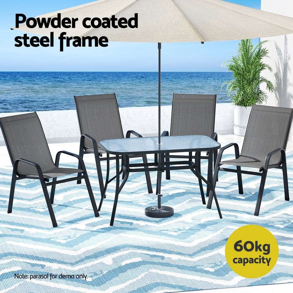 Outdoor furniture set with table and chairs under an umbrella on a beach setting.