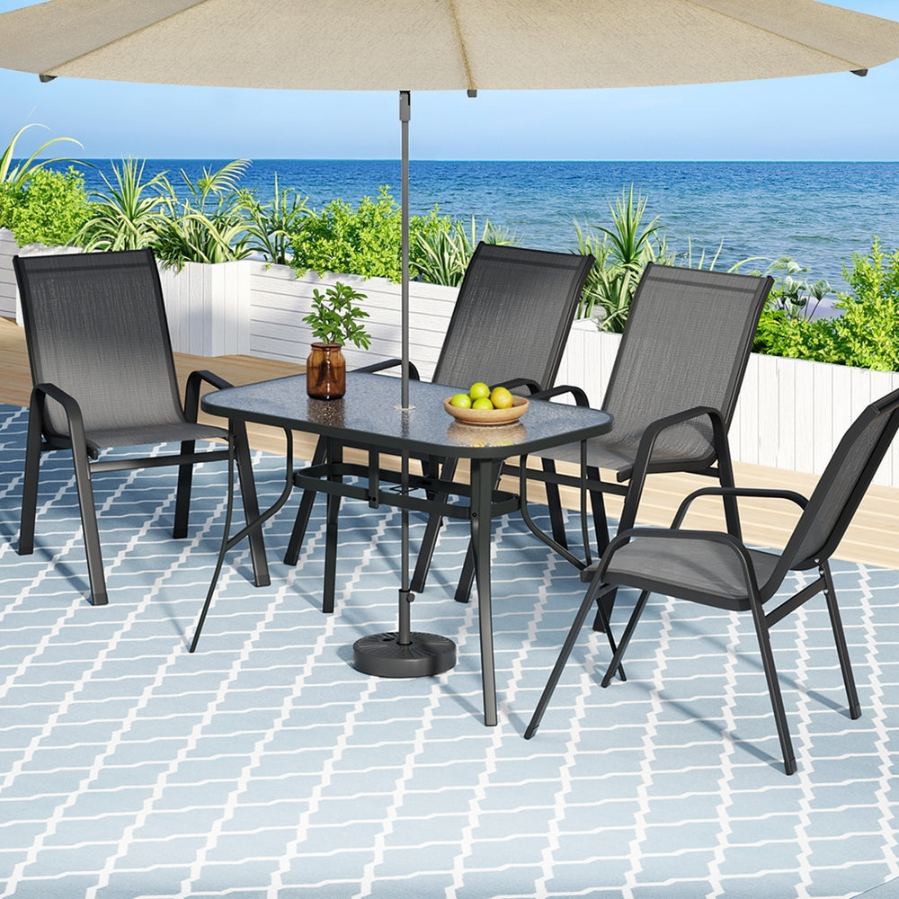 Outdoor patio set with table, chairs, and umbrella by the sea.