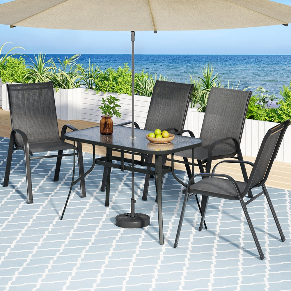 Outdoor patio set with table, chairs, and umbrella on a tiled deck by the ocean.