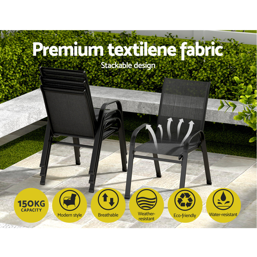 Two black outdoor chairs with textilene fabric on a patio with greenery in the background.