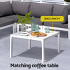 Outdoor furniture set with a coffee table, sofa, and decorative items on a patio.