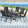 Outdoor dining set with table and chairs under a large umbrella on a patio with ocean view.