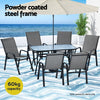 Outdoor furniture set with table and chairs under an umbrella on a beach setting.