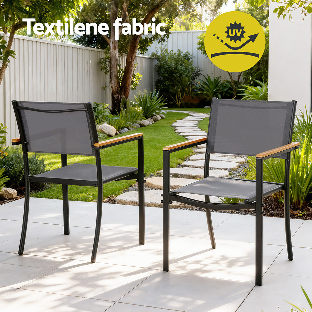 Two outdoor chairs with textilene fabric on a patio area with garden background