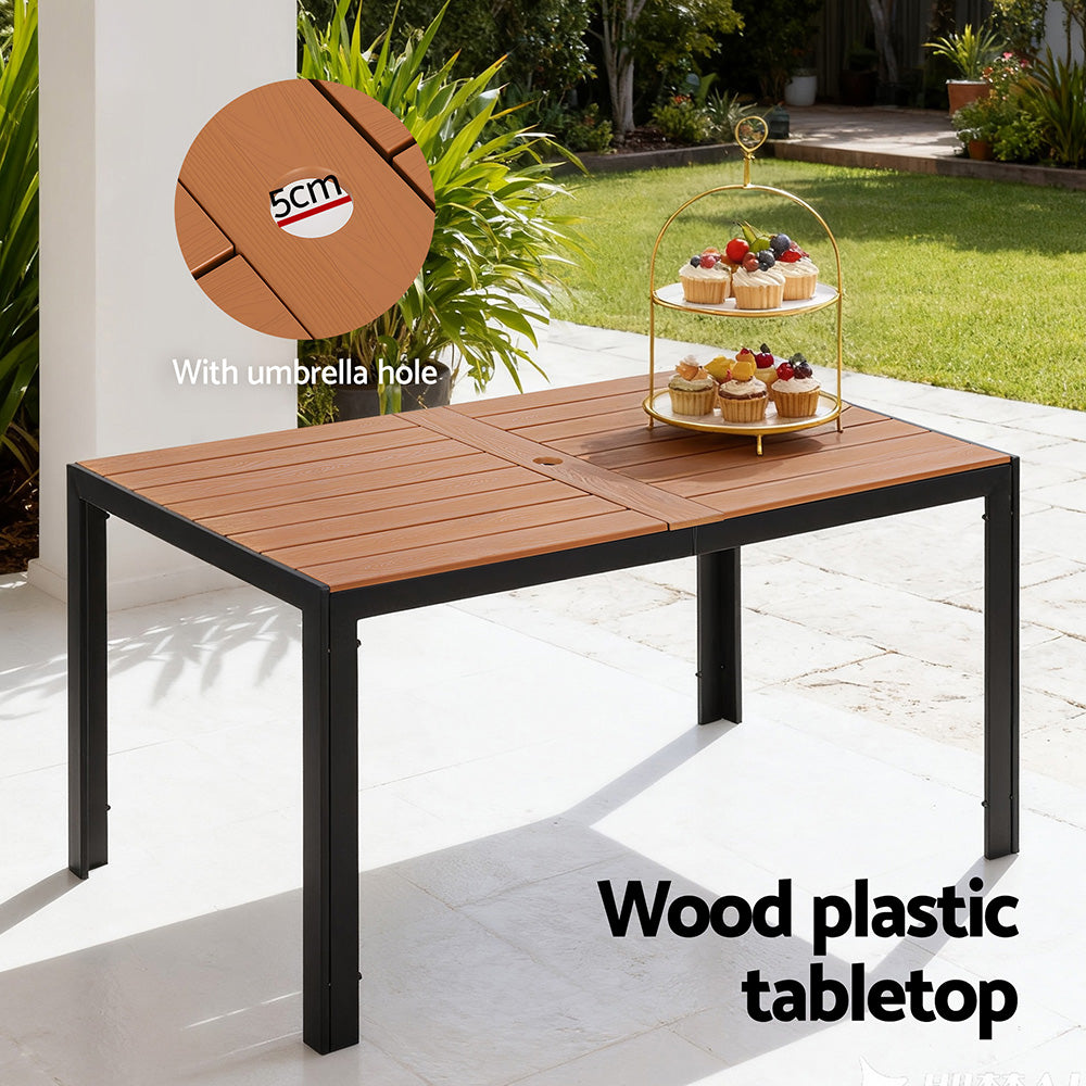Wood plastic tabletop outdoor table with umbrella hole, placed on a patio.