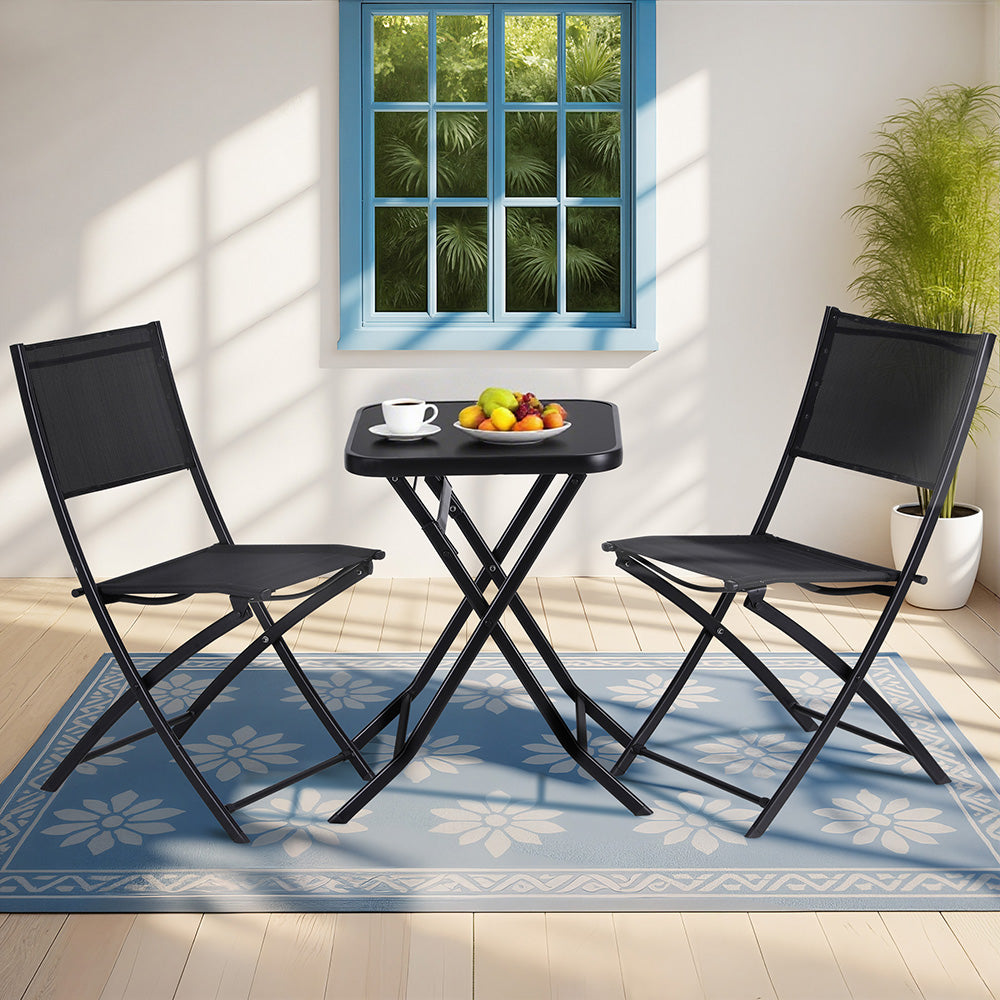 Black folding chairs and table set on a blue rug with a window view in the background.