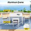 Outdoor dining set with white table and chairs on a deck with ocean view, labeled 'Aluminum frame' and 'Slatted desktop'.