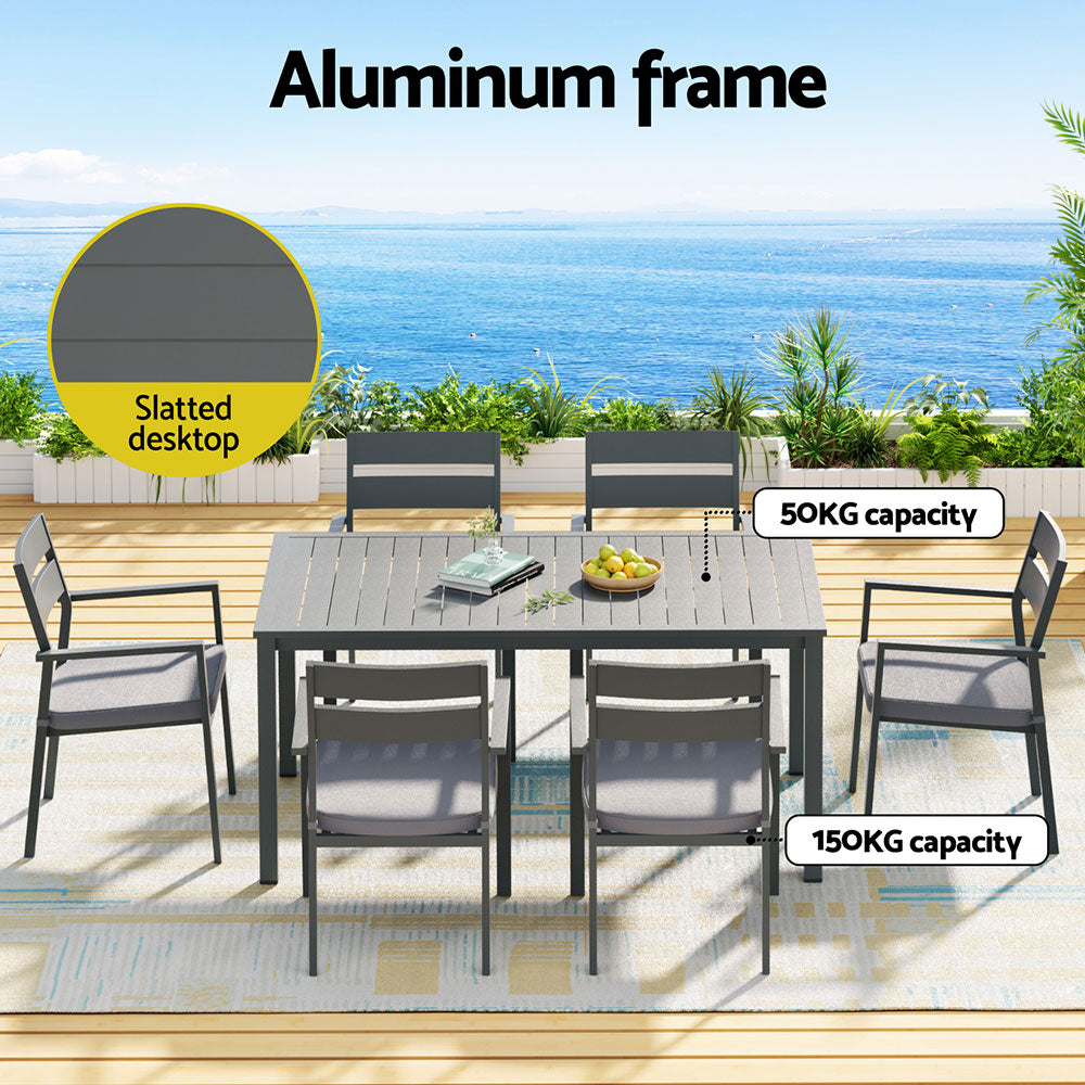 Outdoor dining set with slatted desktop and aluminum frame on a patio with ocean view.