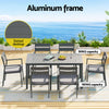 Outdoor dining set with slatted desktop and aluminum frame on a patio with ocean view.