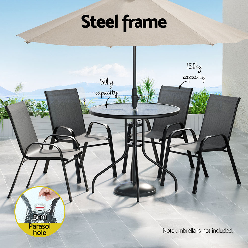 Outdoor furniture set with table, chairs, and parasol on a patio with scenic background