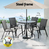 Outdoor furniture set with table, chairs, and parasol on a patio with scenic background