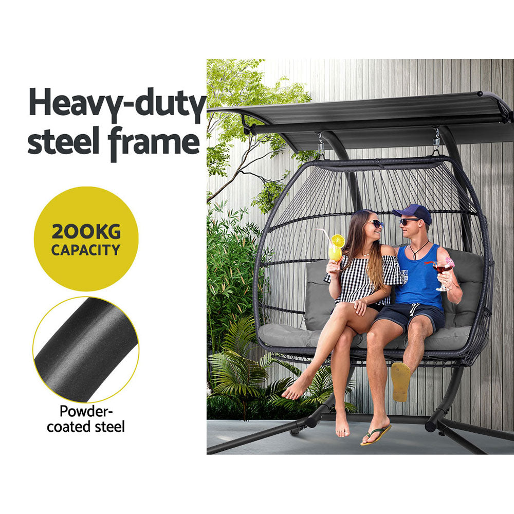 Two people sitting in a hanging egg chair with text highlighting its heavy-duty steel frame and capacity.