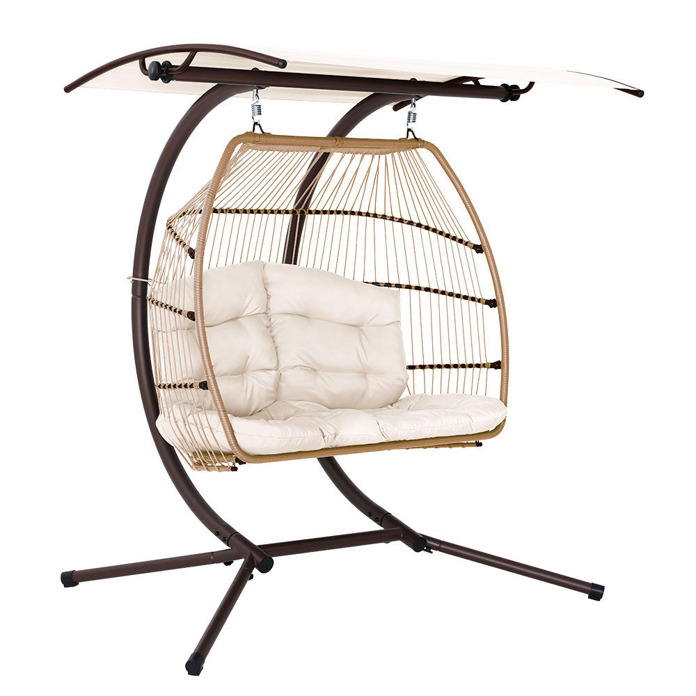 Hanging egg chair with white cushions on a stand against a white background