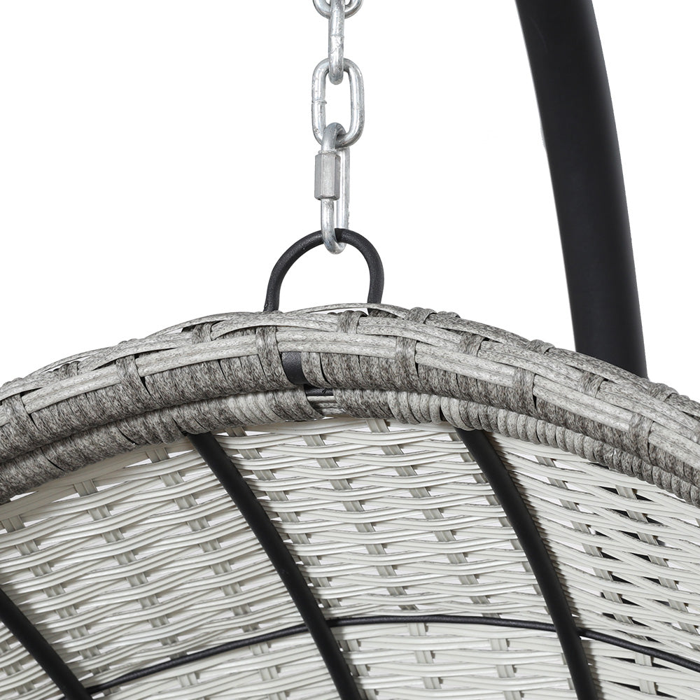 Top view where chain hangs from an outdoor egg swing chair with a grey wicker frame, and charcoal stand on a white background.
