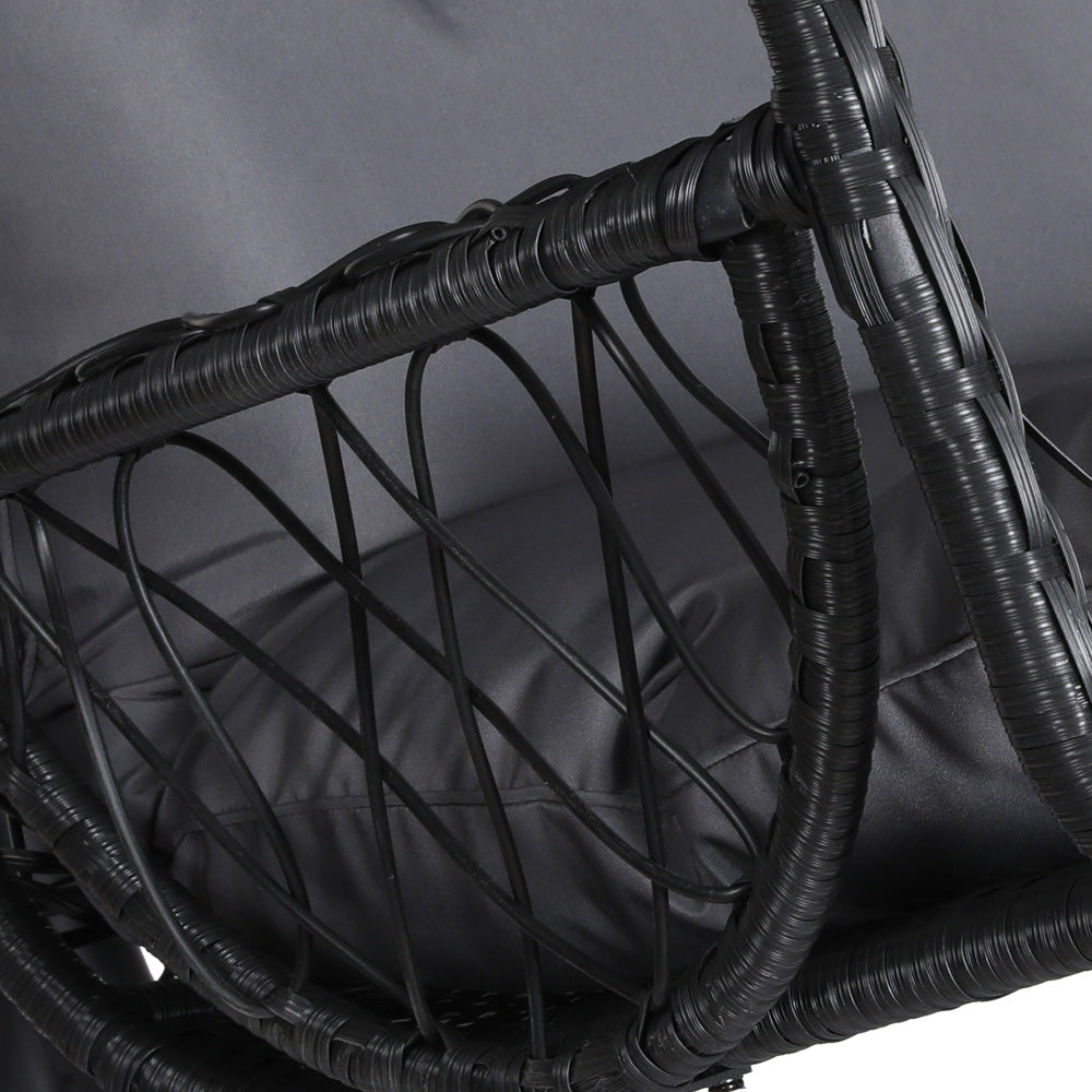 Close-up of a side view of an outdoor egg swing chair with a black wicker frame and grey cushions. 