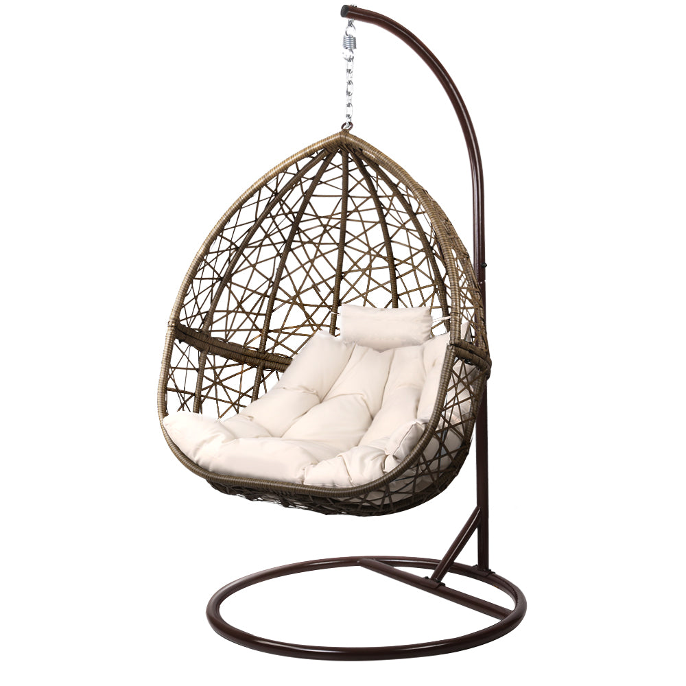 Brown wicker hanging chair with white cushions on a white background