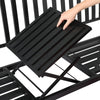 A close up of the foldable table being folded down in a black steel outdoor garden bench in a powder-coated finish and set on a white background.