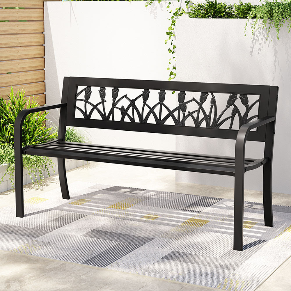 Black metal bench with decorative backrest on a patio