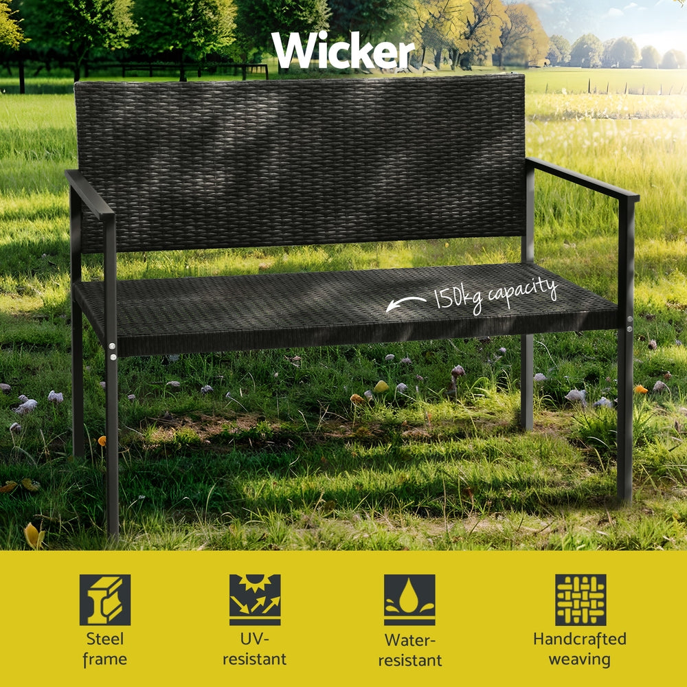A 2-seater Gardeon outdoor garden bench with a grey rattan seat and black powder-coated steel frame showing it has a weight capacity of 150kg in a garden setting with trees in the background.