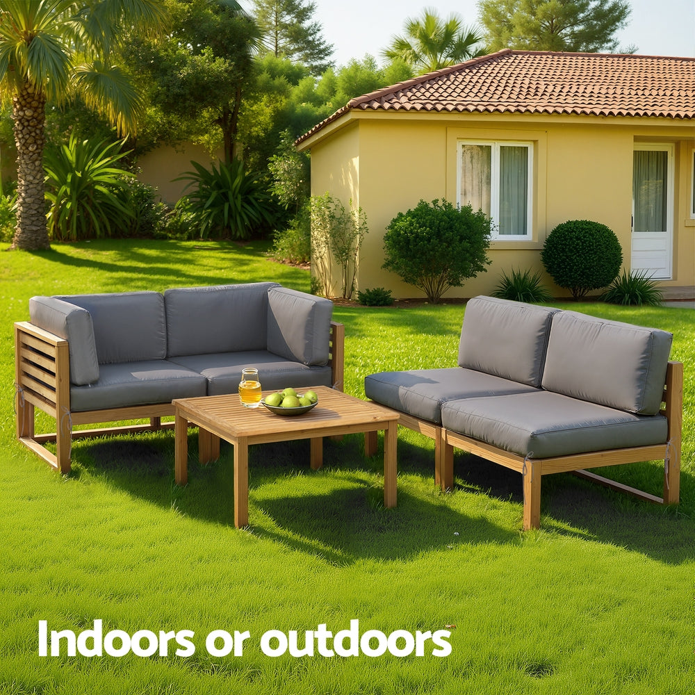 Outdoor furniture set with gray cushions on a grassy lawn in front of a house.