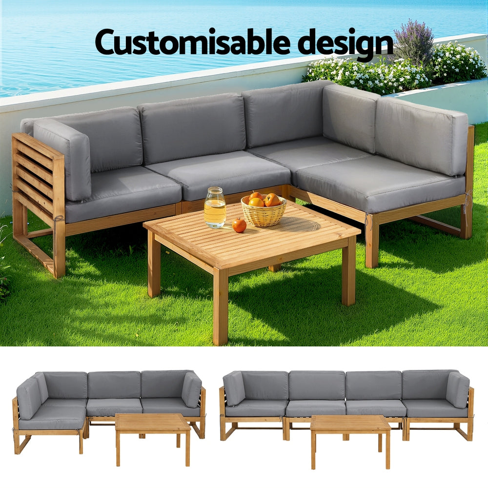 Outdoor furniture set with wooden frame and gray cushions on a grassy area.