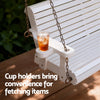 White wooden swing with a cup holder containing a drink on a wooden deck.