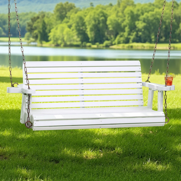 White wooden swing set in a grassy area with a lake and trees in the background