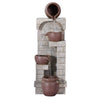 A brown, four-tier cascading water fountain feature with bowls set against a textured wall. Made from polyresin, showing water flowing from the top bowl to the bottom one, set on a white background.