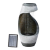 Solar-powered fountain with a cascading design, featuring a grey sculptural structure and a solar panel beside it, meant for outdoor garden use.