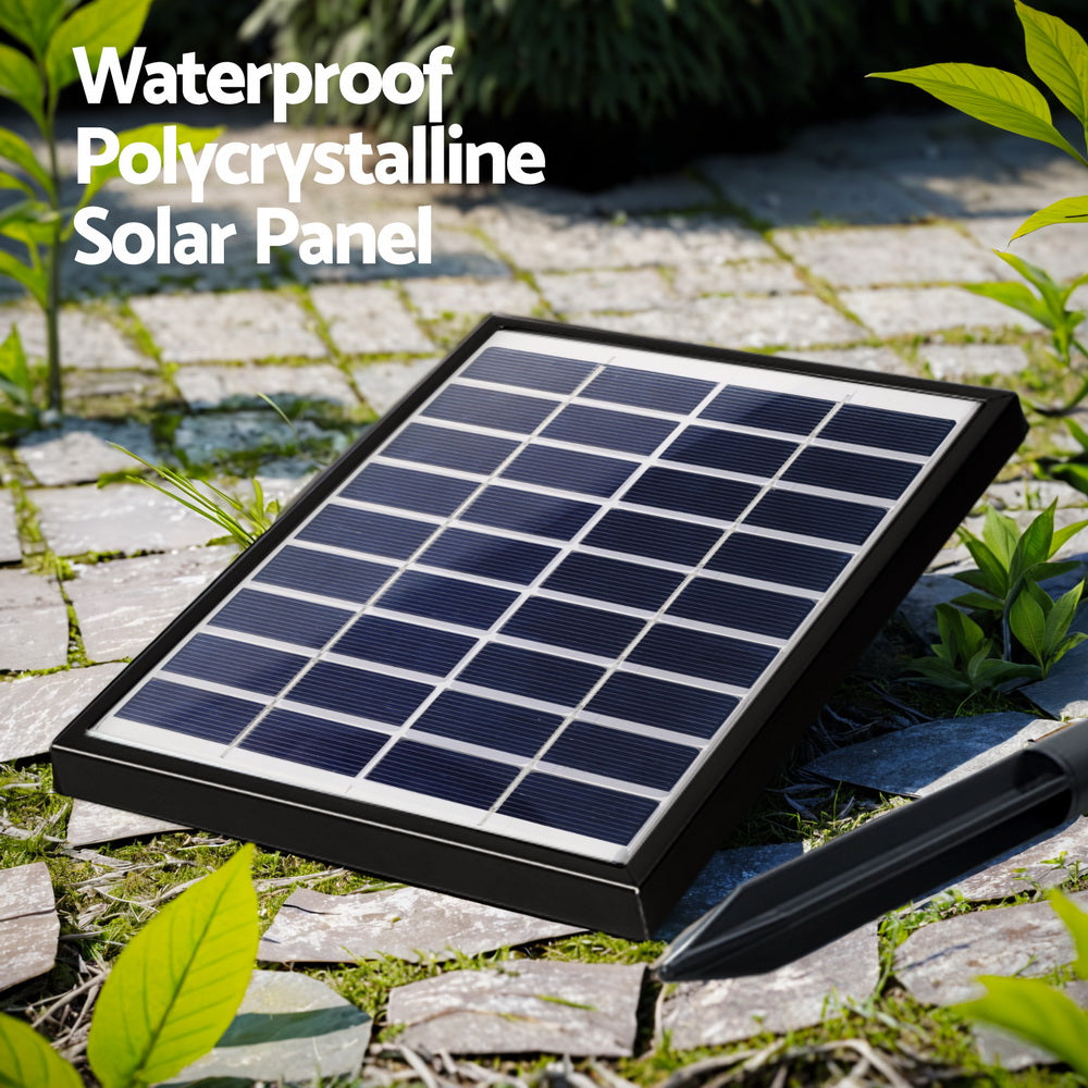 The solar panel to water fountain set up in a garden on some slate paving and small greenery growing between the pavers.
