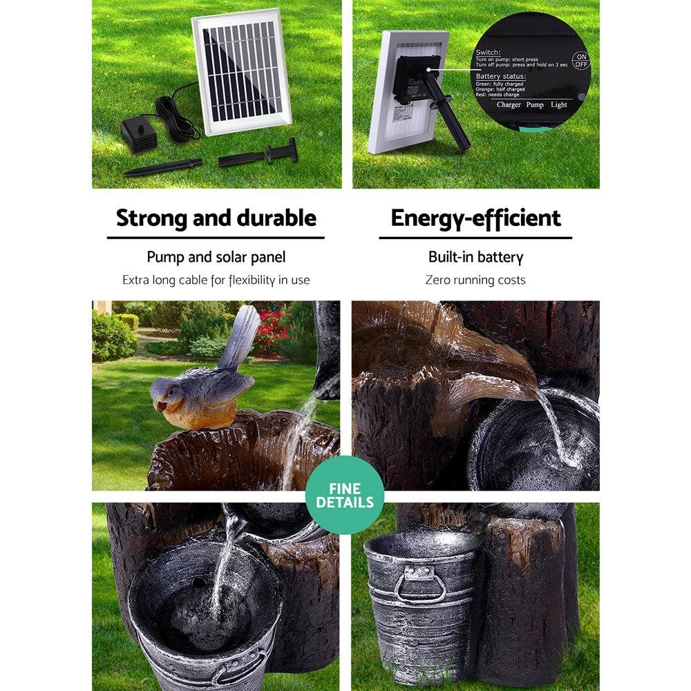 The three-tier cascading water feature with buckets, featuring six split photos showing different close-up views of the cascading water pouring from the buckets to the one below. One image of a bird sitting on the tree stump. The fountain is in a garden setting with grass and flower beds in the backdrop. 2 images showing the solar pump from back and front views.