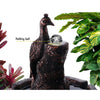 Close up of the peacock and featuring a rolling ball at the top a brown water fountain with plants and on a white background.
