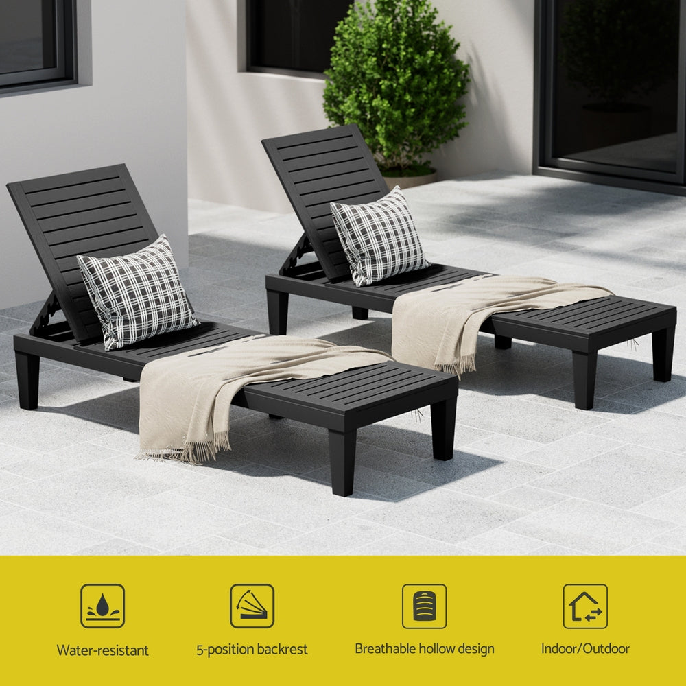 Two black outdoor lounge chairs with cushions and blankets on a patio.