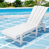 White lounge chair by a pool with greenery in the background