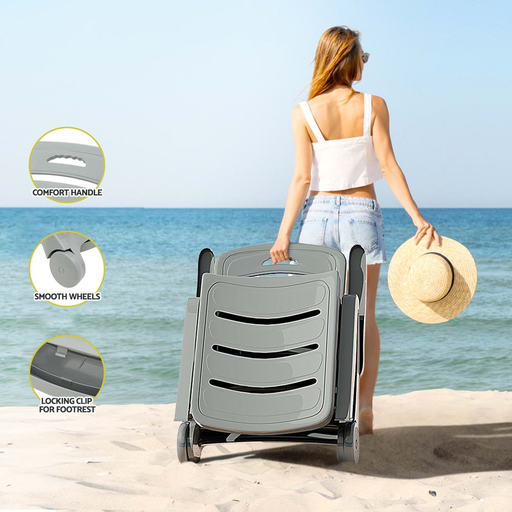 A young woman wheeling a foldable sun lounger across the sand heading toward the water at a beach and holding a sunhat in her other hand. There are 3 inset close-up images showcasing its locking clip for footrest, smooth wheels and comfortable handle.