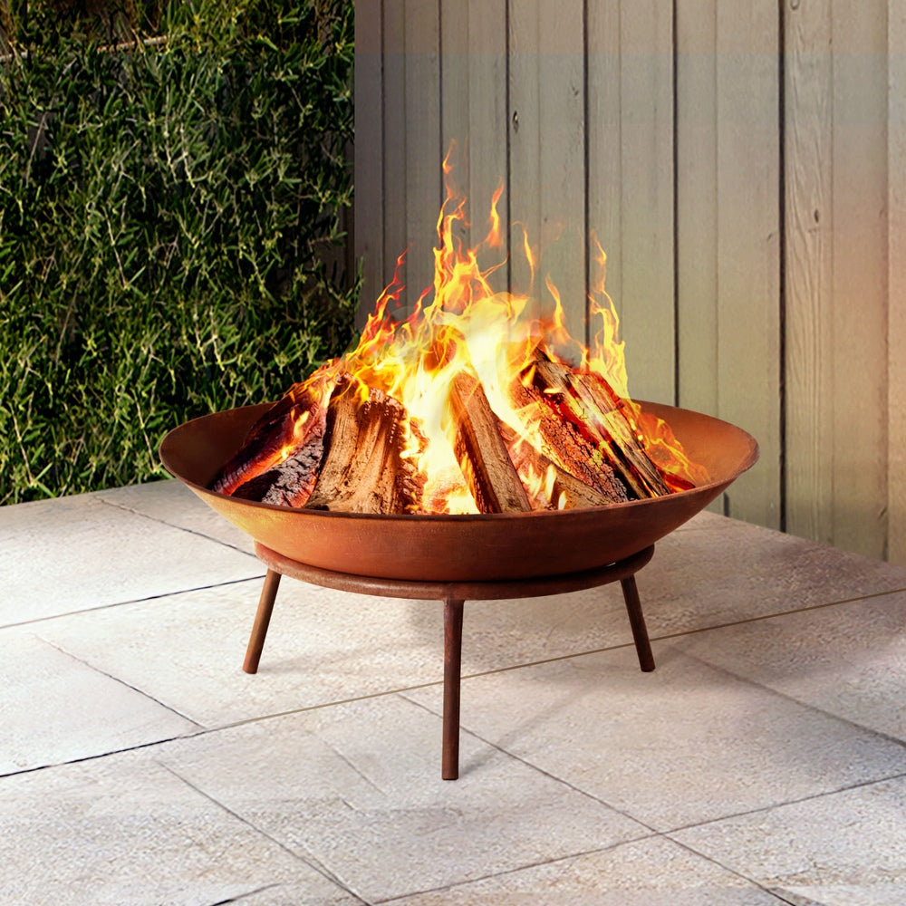 Corten steel fire pit with flames on a patio