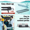 Product with removable charcoal tray for easy clean-up and carrying, shown in a car trunk with people around.