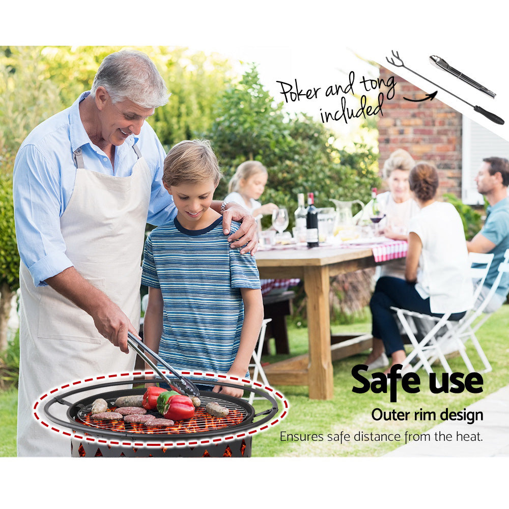 A man cooking on BBQ grill, with his arm around a young boy, both and smiling and family can be seen sitting behind them at a picnic table in a garden setting with house and trees in the background.