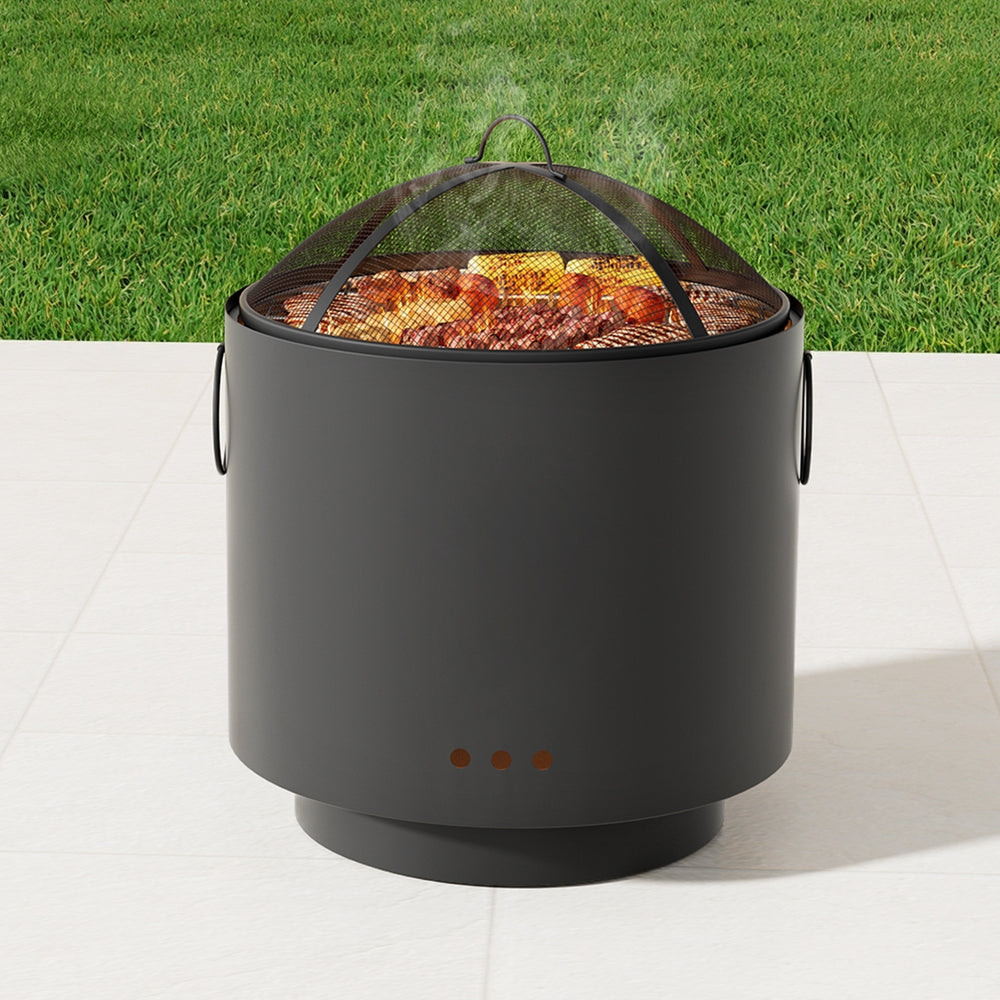 Black cylindrical fire pit with grill grate on a grassy background